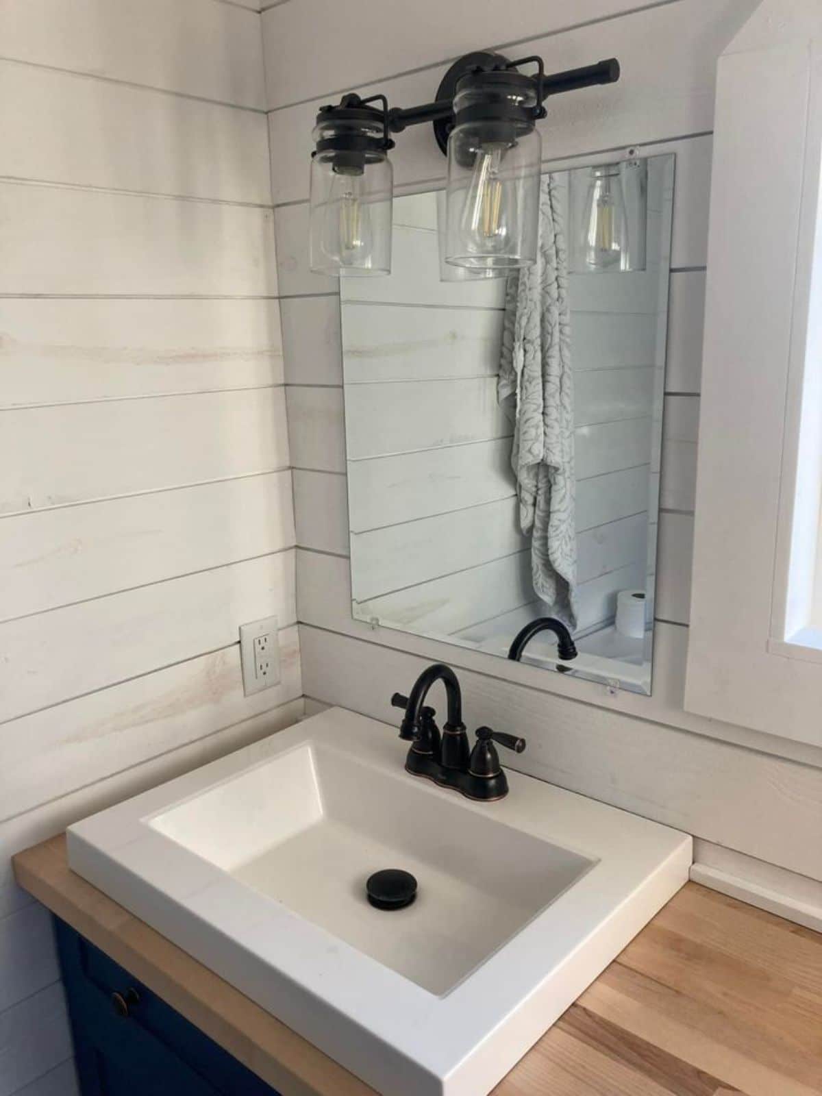 white square sink below mirror on shiplap walls in bathroom