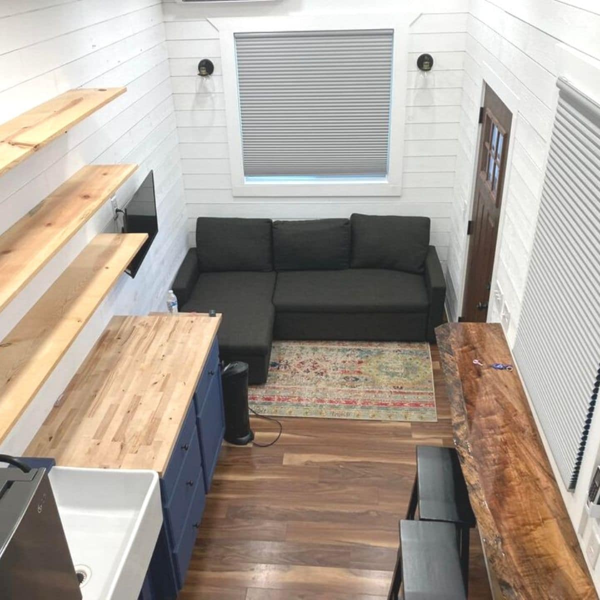 white shiplap walls inside tiny house with black sofa against back wall