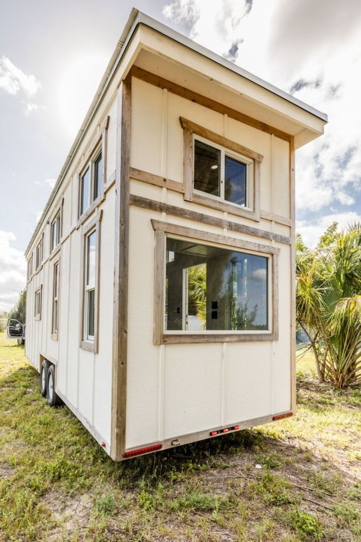 white tiny home with wood trim and windows on the end