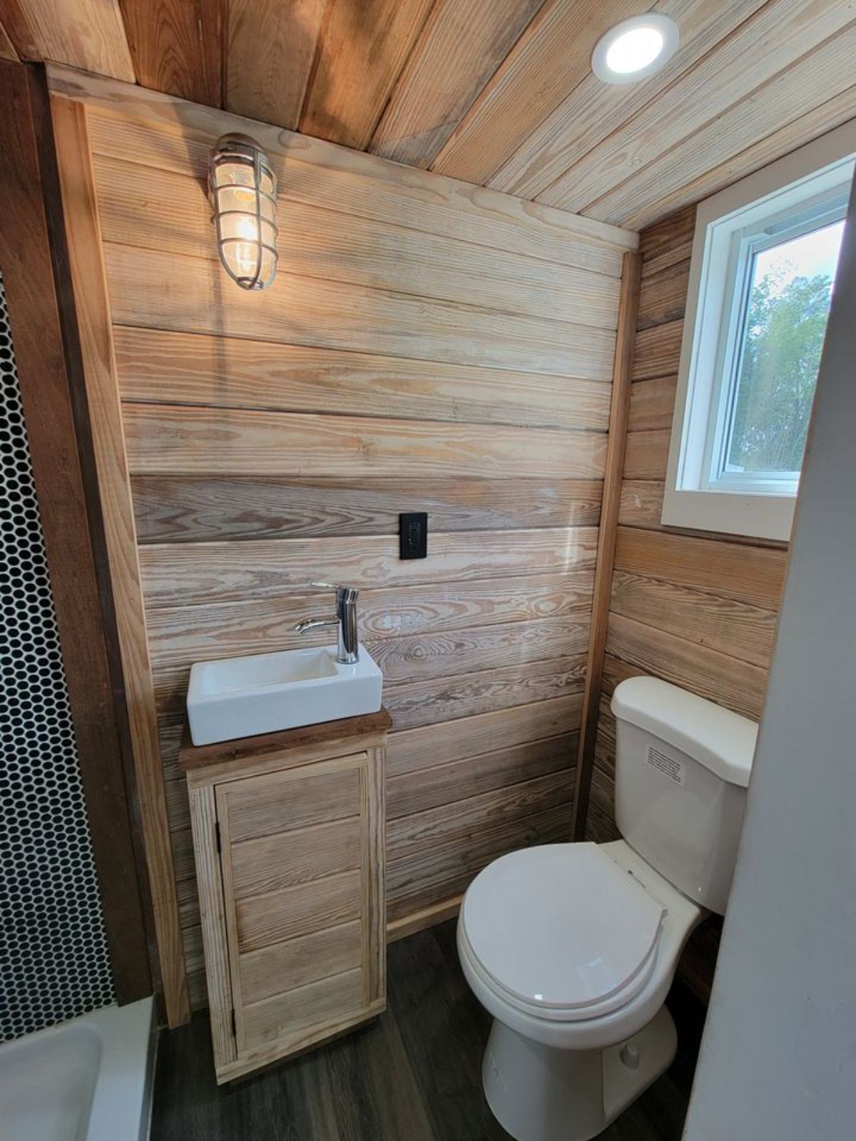 small white sink against wood wall in bathroom