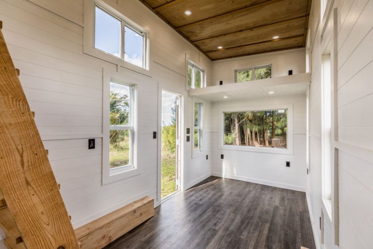 open door on side of tiny home with white walls and dark wood ceiling