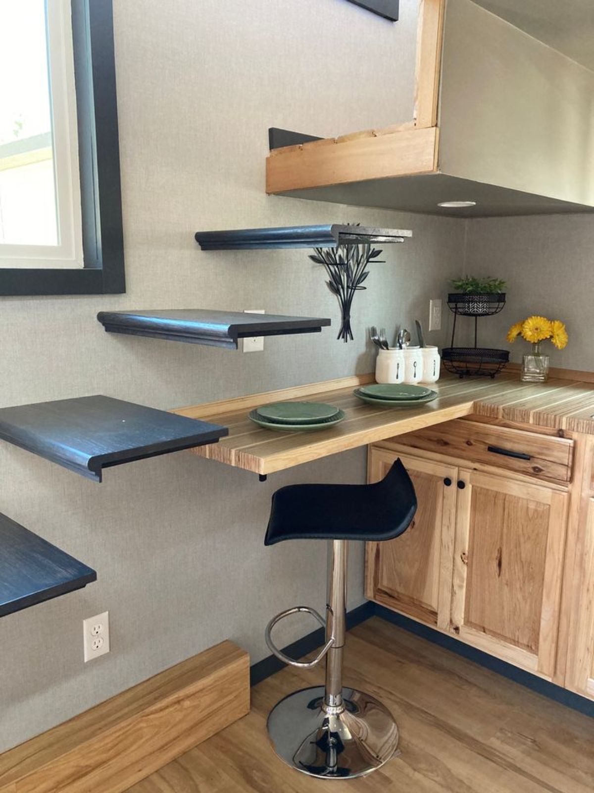 light wood table beneath floating gray stairs to loft in tiny home