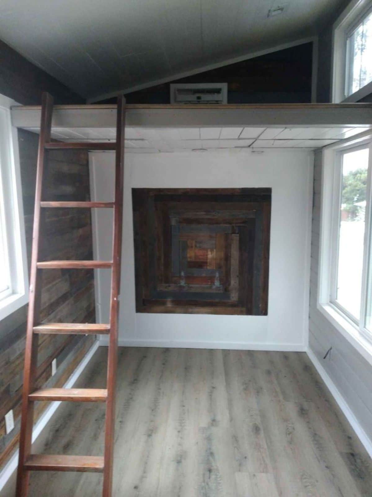ladder to loft on left of image with reclaimed wood block beneath loft against white wall