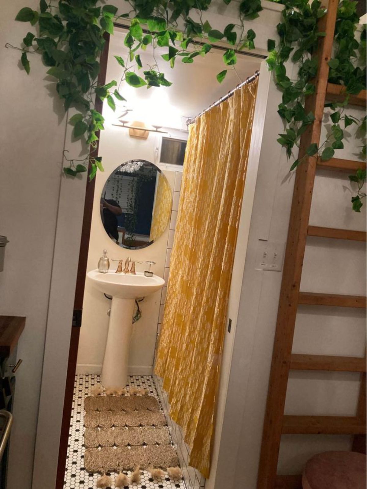 open door to bathroom with gold shower curtain inside tiny home