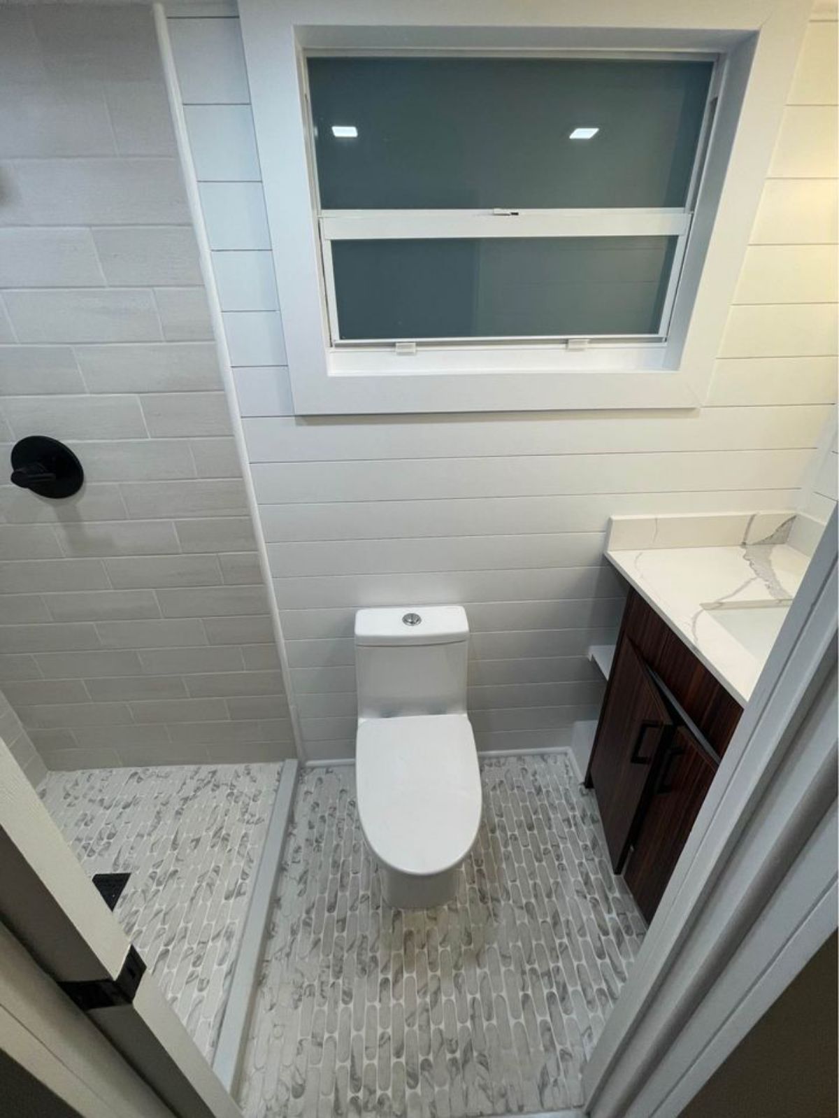 flush toilet between dark wood vanity and tiled shower stall