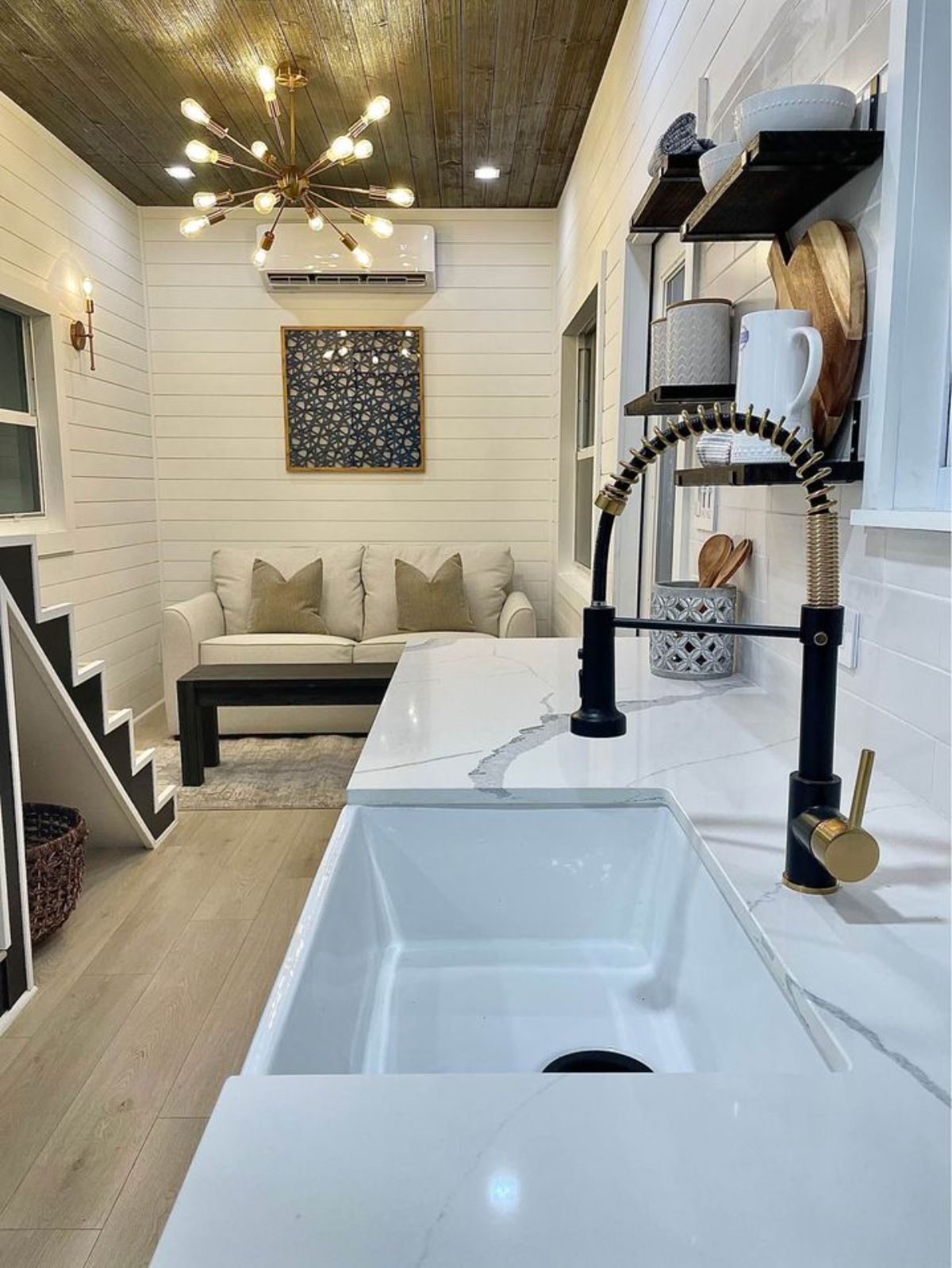 black faucet over white sink in white marble counter of tiny house kitchen