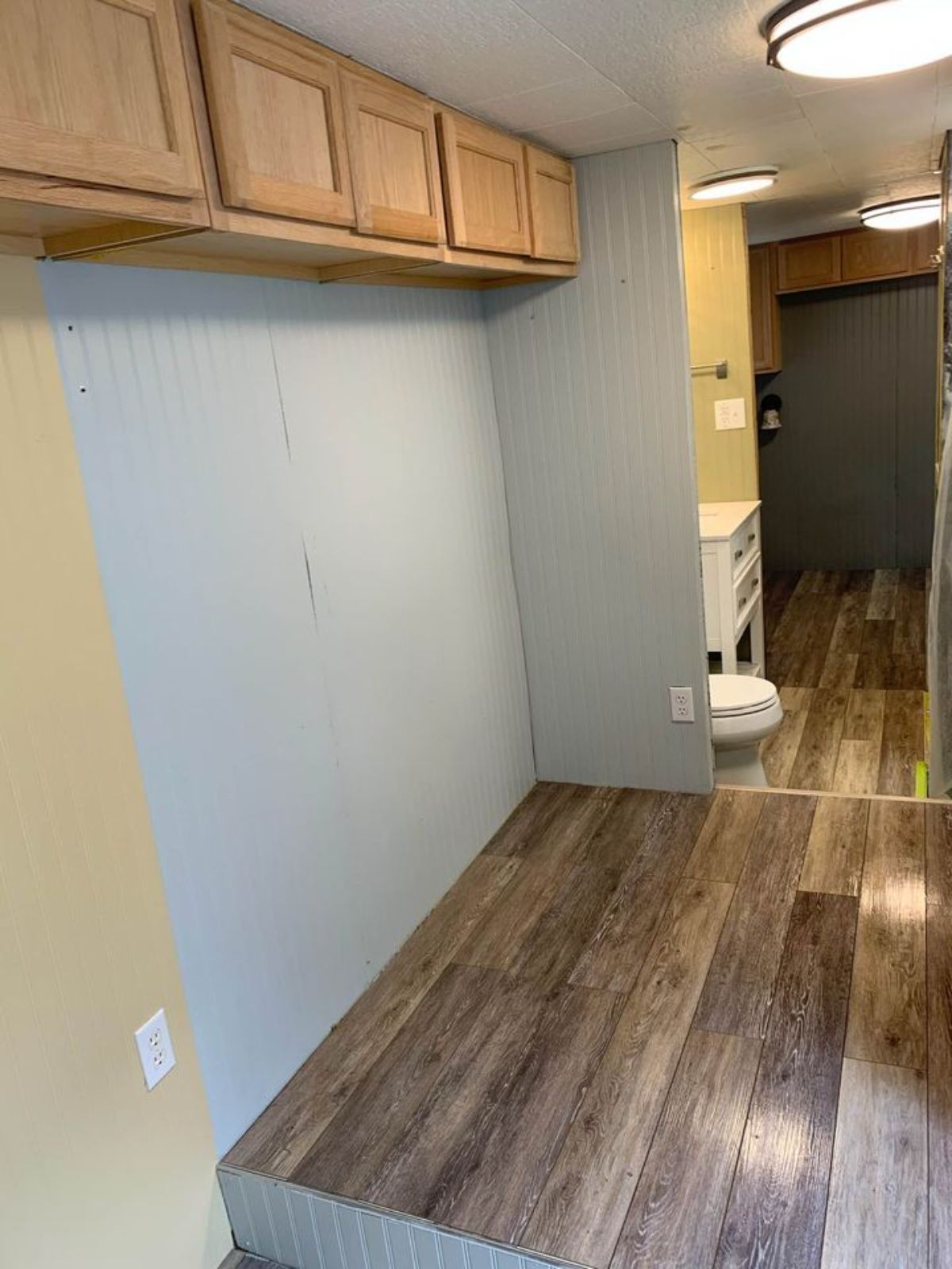 light gray walls with wood flooring podum beneath cabinets in tiny home