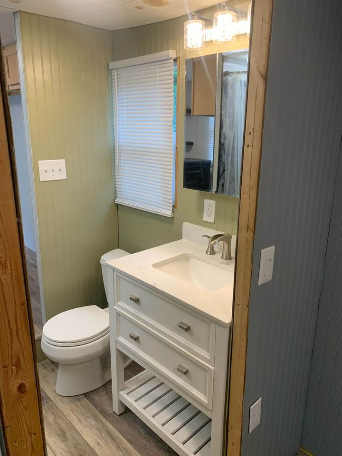 white vanity next to flush toilet in tiny house bathroom