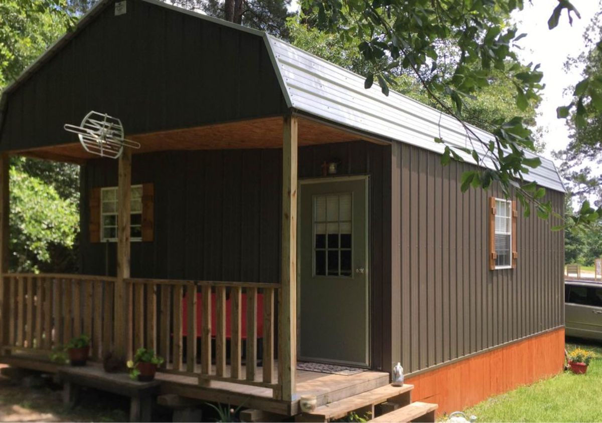 converted she with covered porch and gray siding