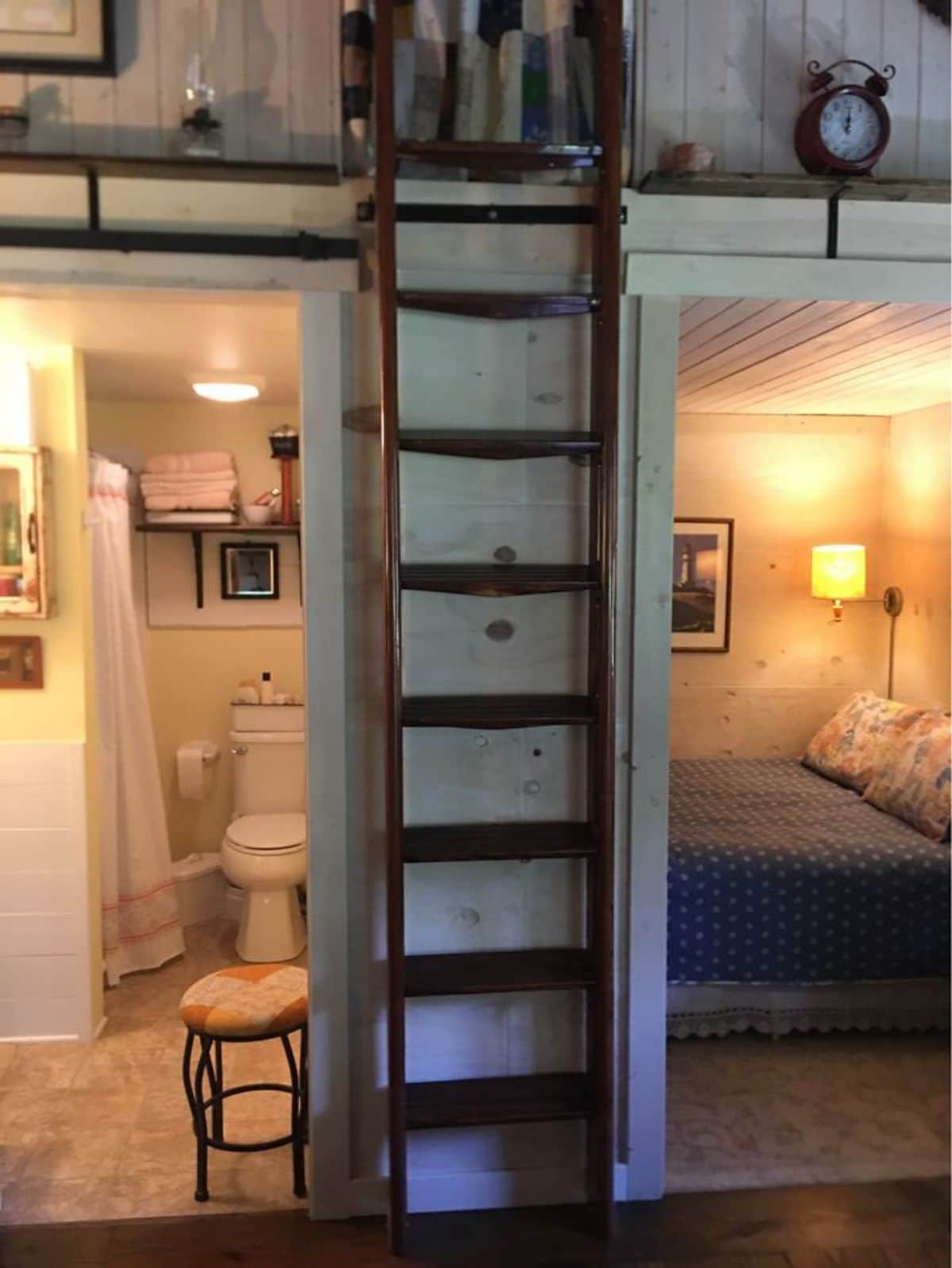 wood ladder between two open doors with bedroom and bathroom on either side