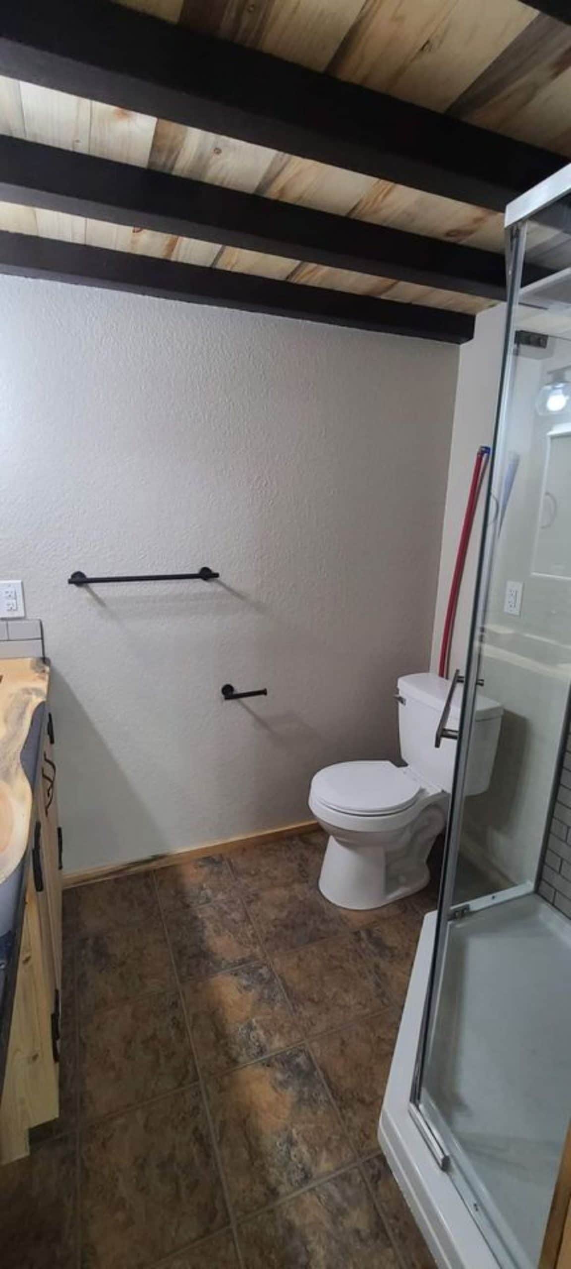 toilet against white wall with glass wall shower