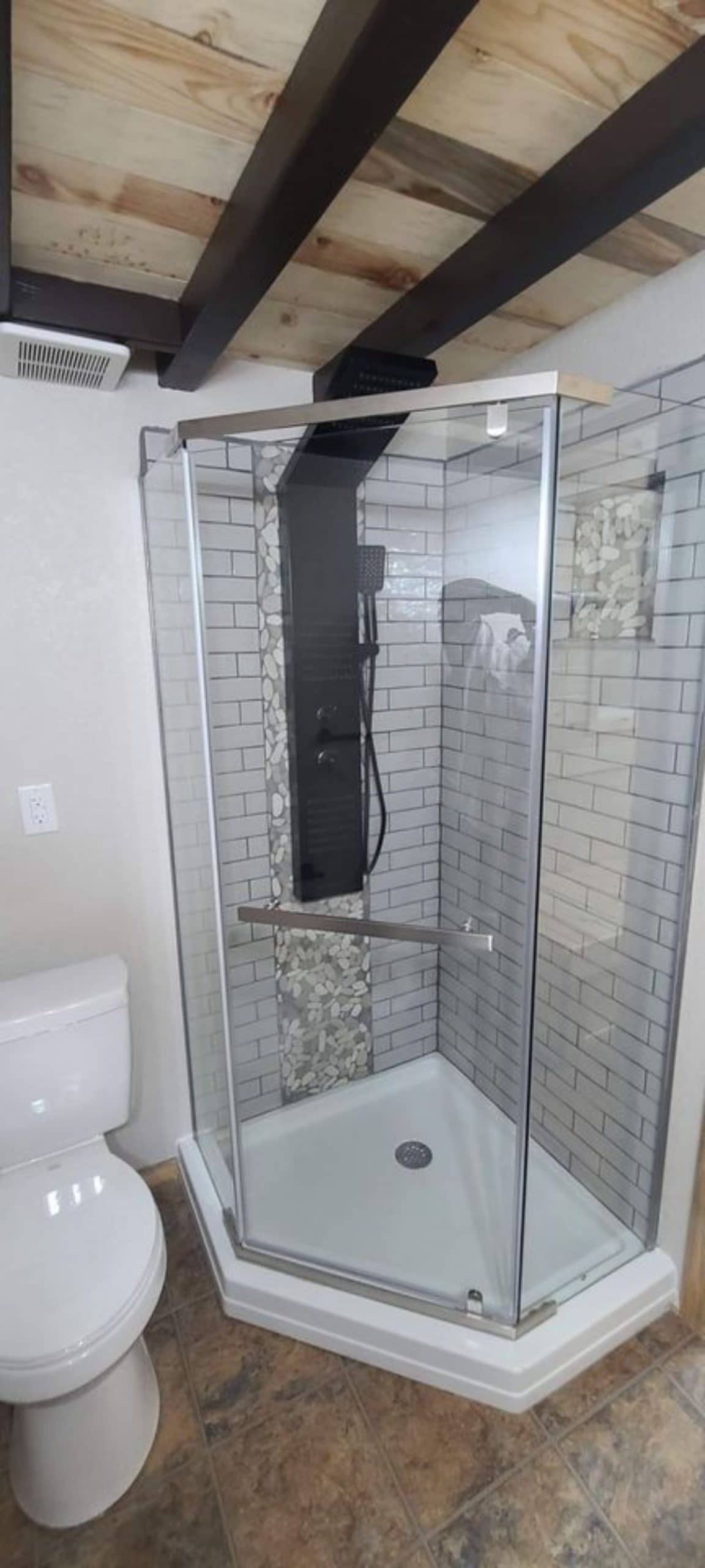 glass wall shower with grey tile and black fixtures