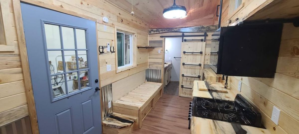 wood bench seat against wall of tiny home by blue door