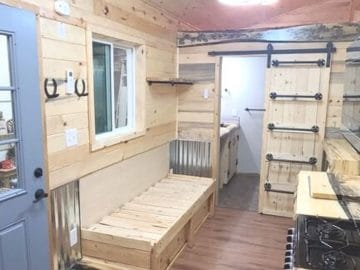wood bench seat against wall of tiny home by blue door