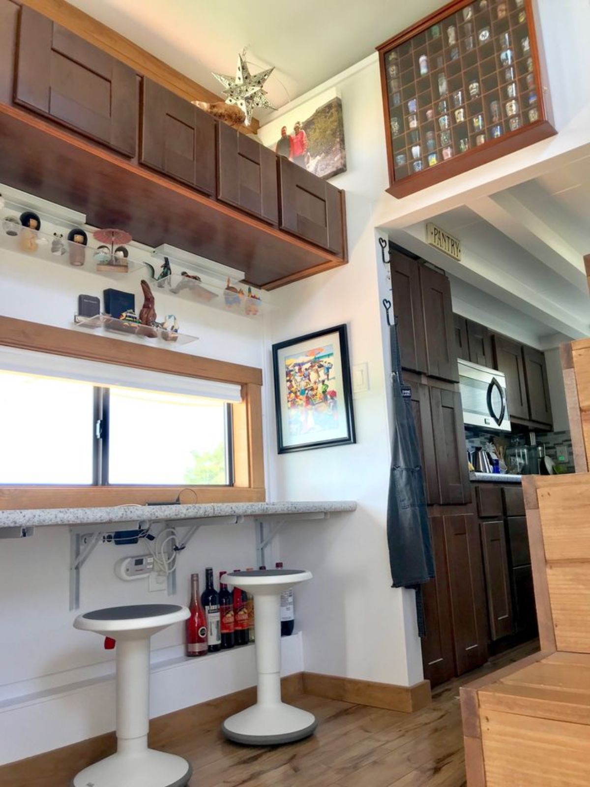 white stools under counter beneath window next to wall to tiny home kitchen
