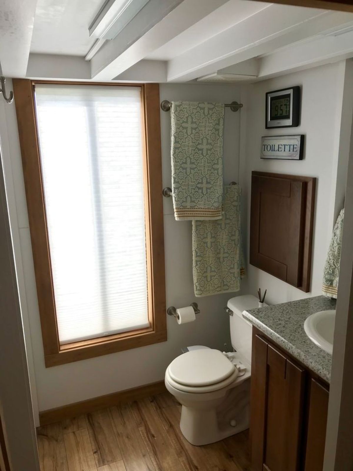 flush toilet beside wood vanity with white sink in bathroom