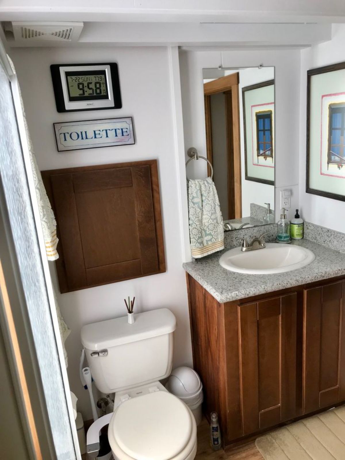 dark wood door above white toilet in bathroom and wood cvanity with white sink and counter