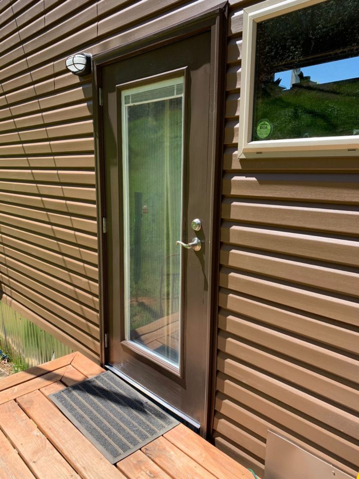 dark brown trim around glass front door against brown siding