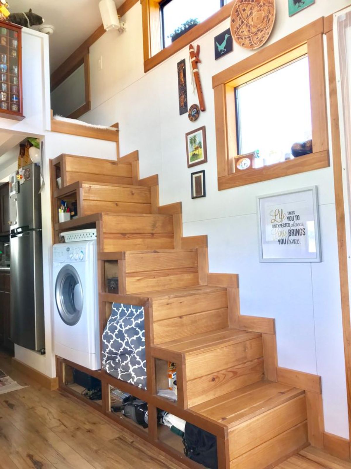 white combination washer and dryer beneath wooden stairs to loft with white wall background