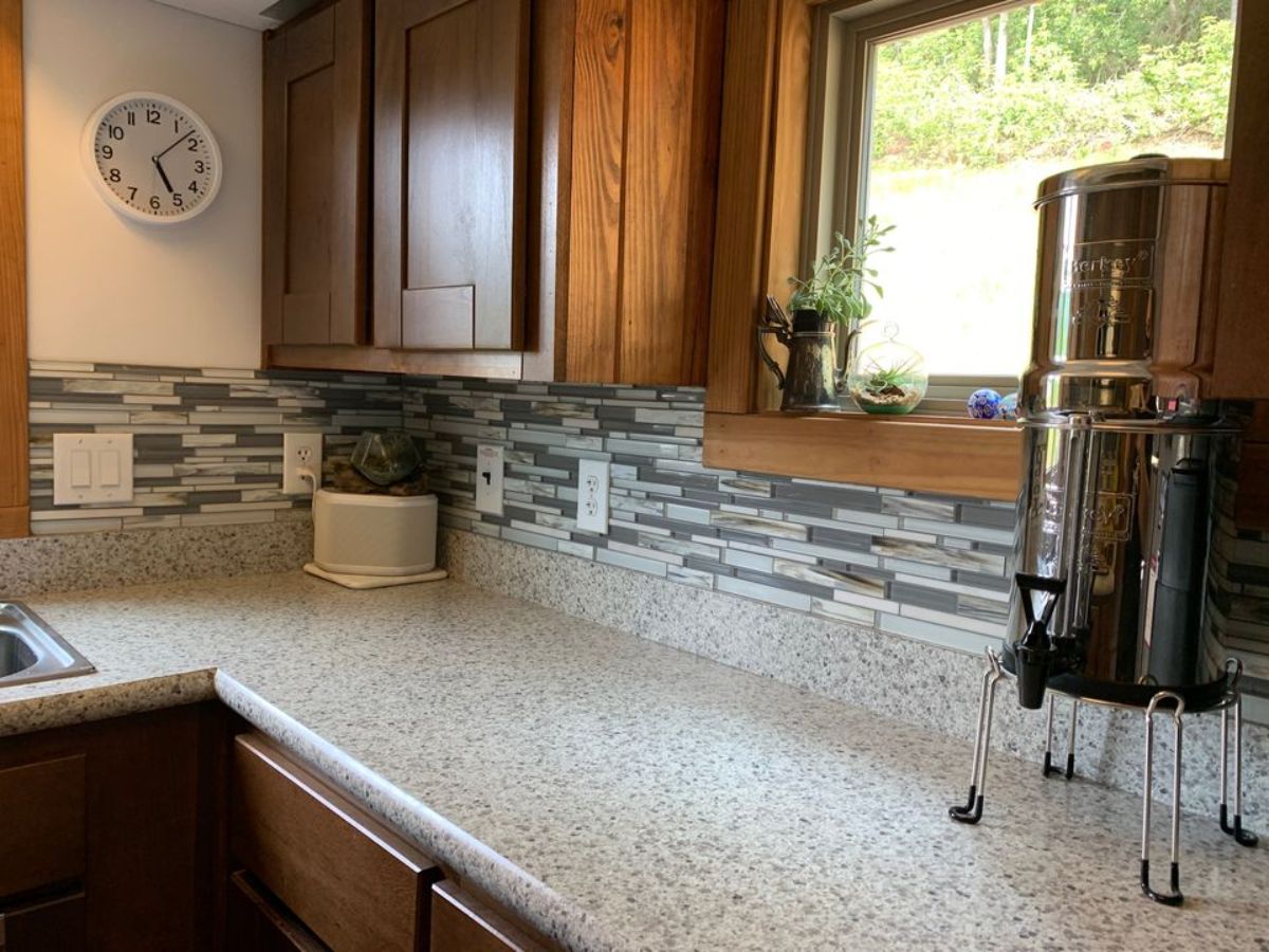 light granite counters with tile backsplash below dark wood cabinets in kitchen