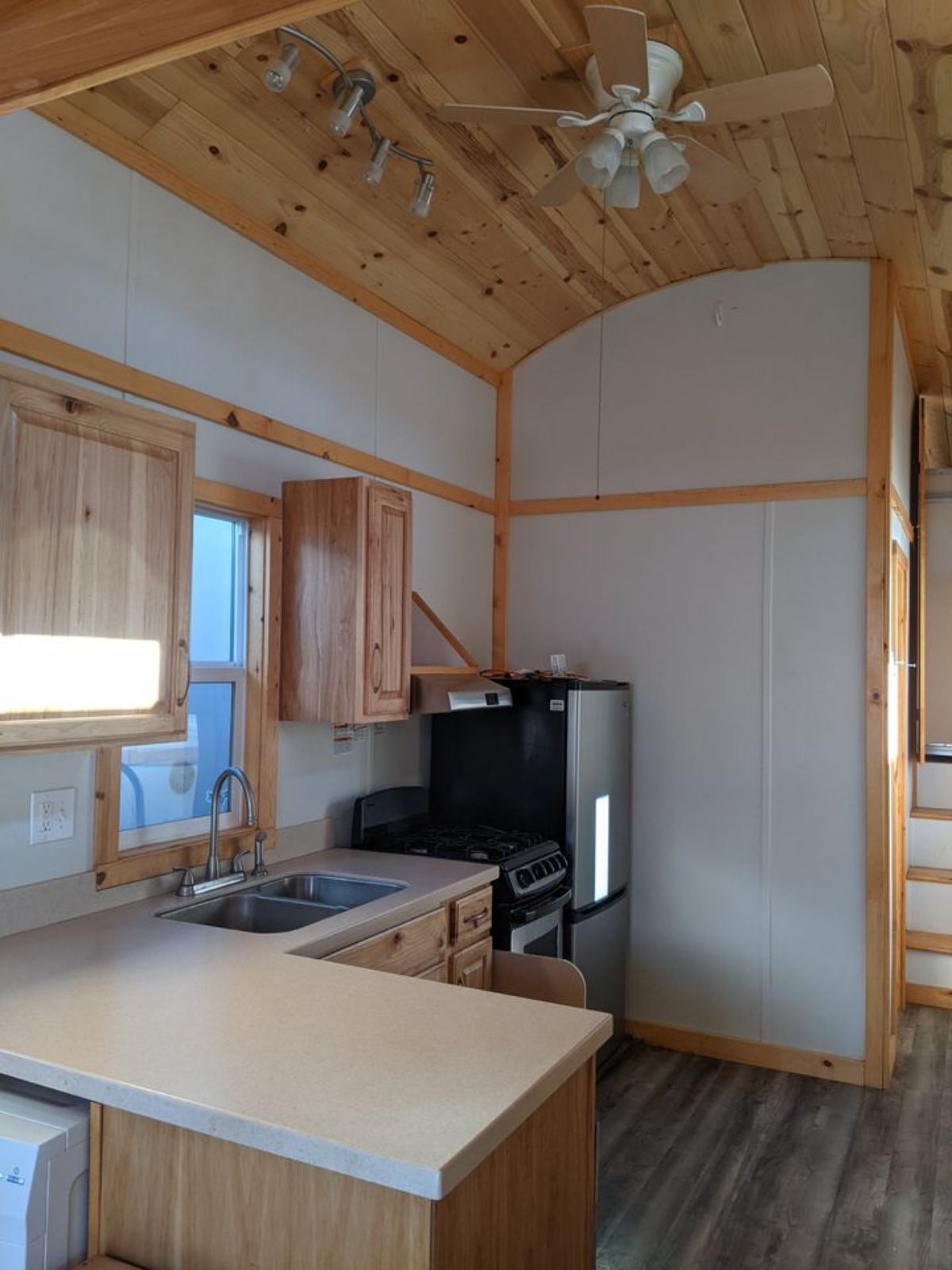 Kitchen area with gas burner, kitchen cabinets and refrigerator with ample space in 35' Spacious Tiny House