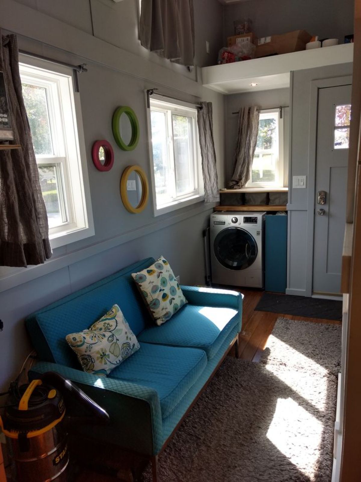 Living area of of 196 sf Tiny House on Wheels has a couch and washer dryer
