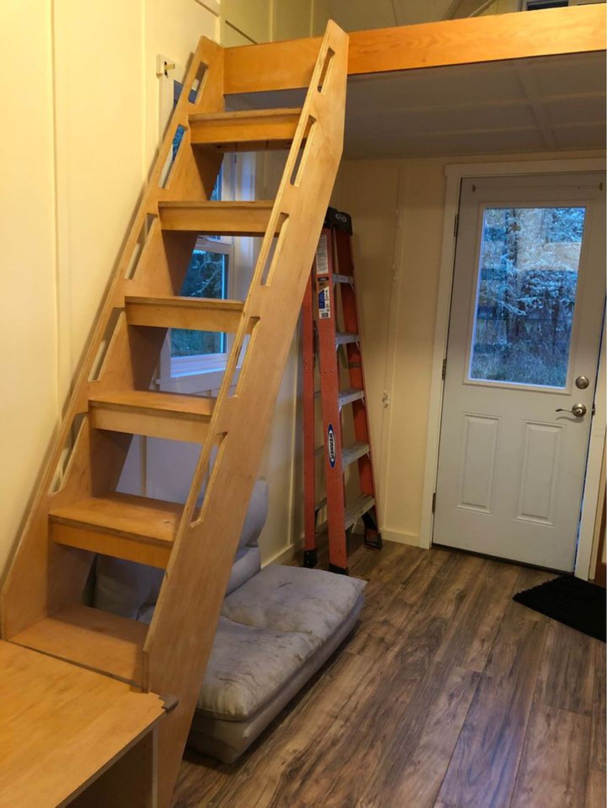 Living area has couch just besides the ladder for bedroom