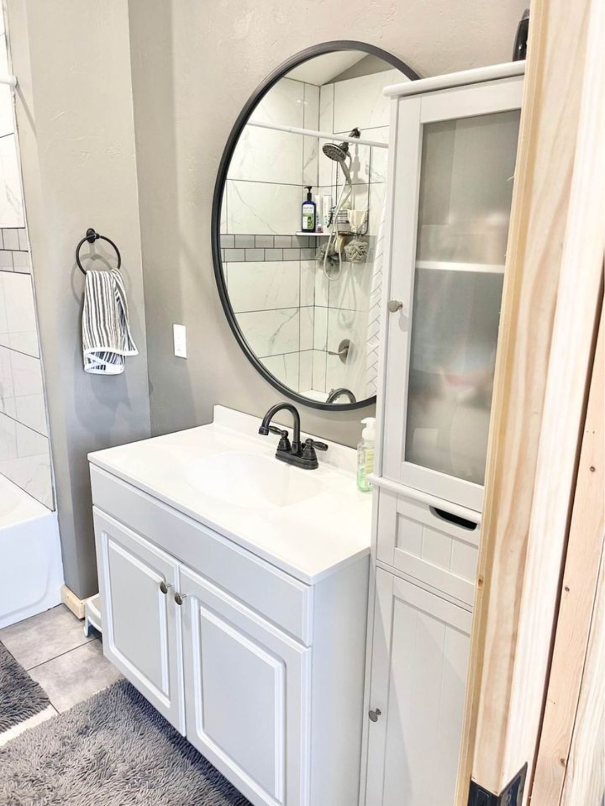 Stylish bathroom of 42’ Tiny Househas a sink with vanity, mirror and storage