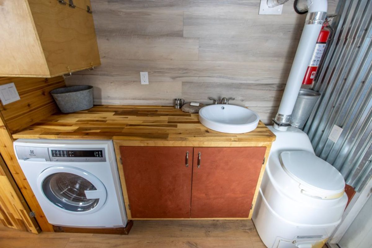 Washer/dryer, sink and toilet in bathroom of Custom Tiny Home on wheels