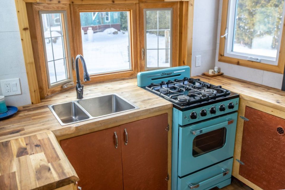 4 burner stovetop oven and sink in the kitchen of Custom Tiny Home on wheels