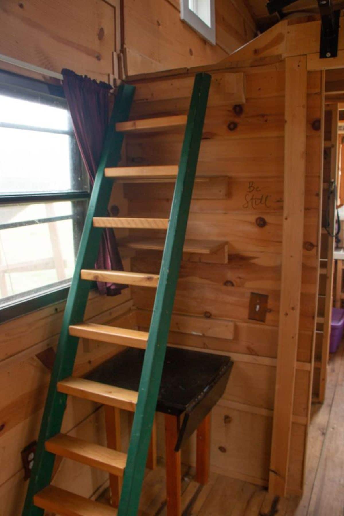 the bedroom is accessible through the ladder which has some drawers and storage under it