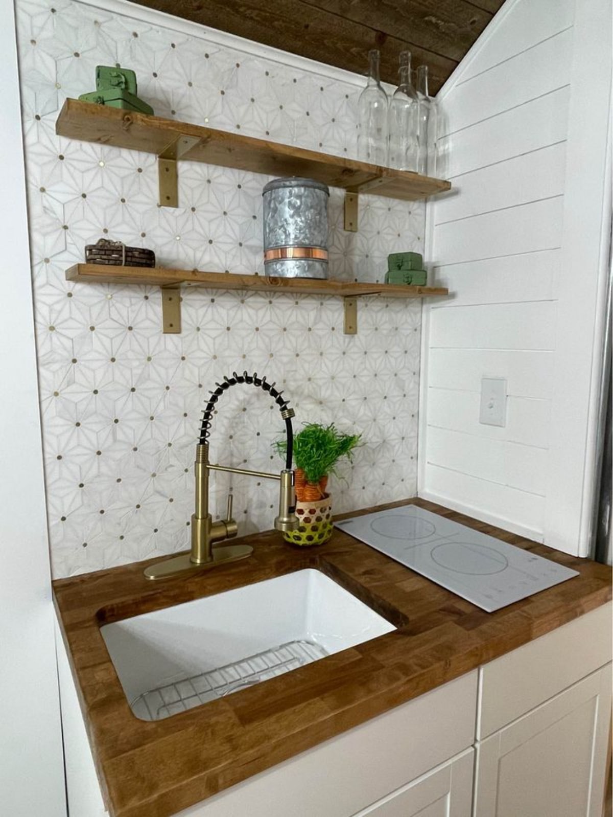 Kitchen area of 16' Compact Tiny House has a sink, a cooktop and some open shelves.