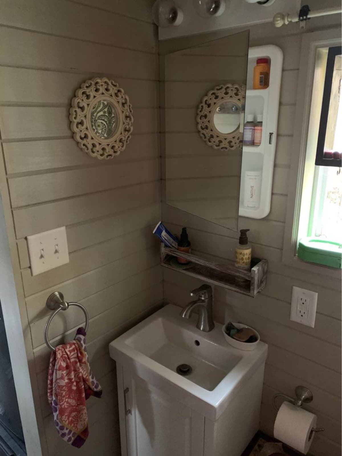 Mirror and sink in bathroom of 180 sf Adorable Tiny House on Wheels
