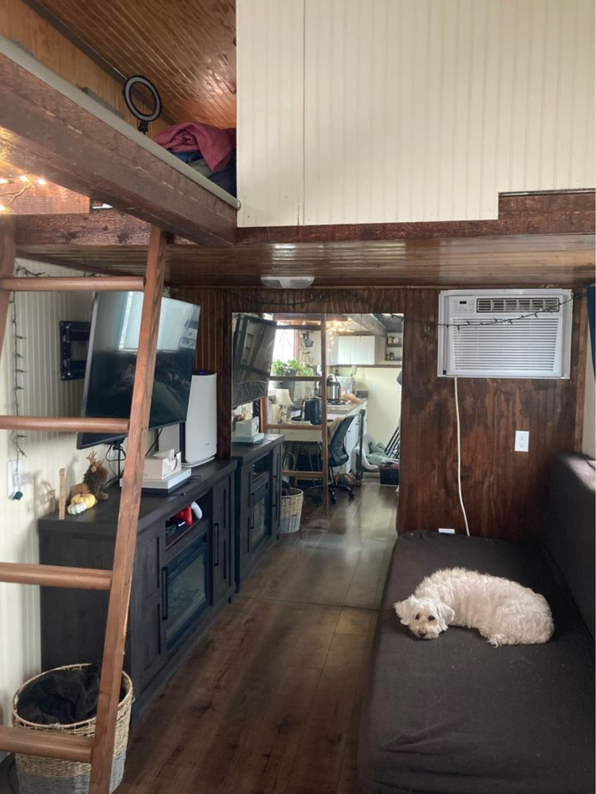 Living space of 30' Budget-Friendly Tiny House has a couch, television unit, storage cabinets and an air condition unit