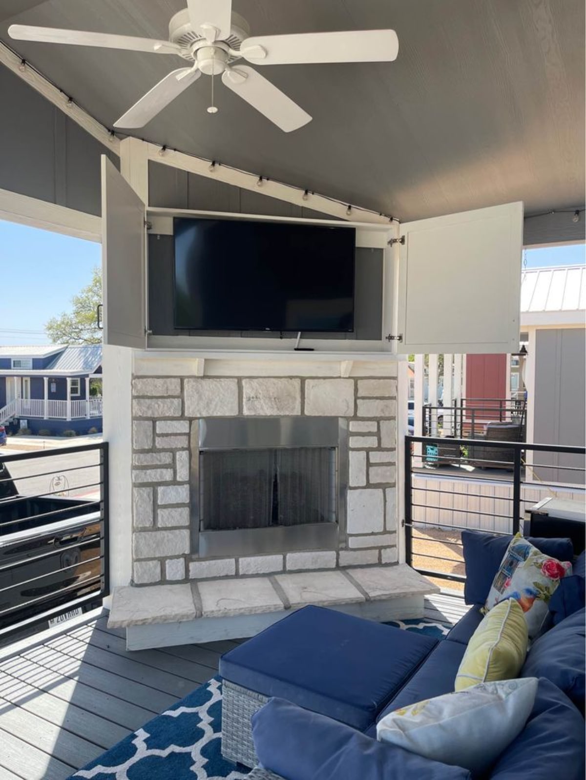 Patio outside the Champion-Built Park Model Tiny House has a sofa, a television set and fireplace
