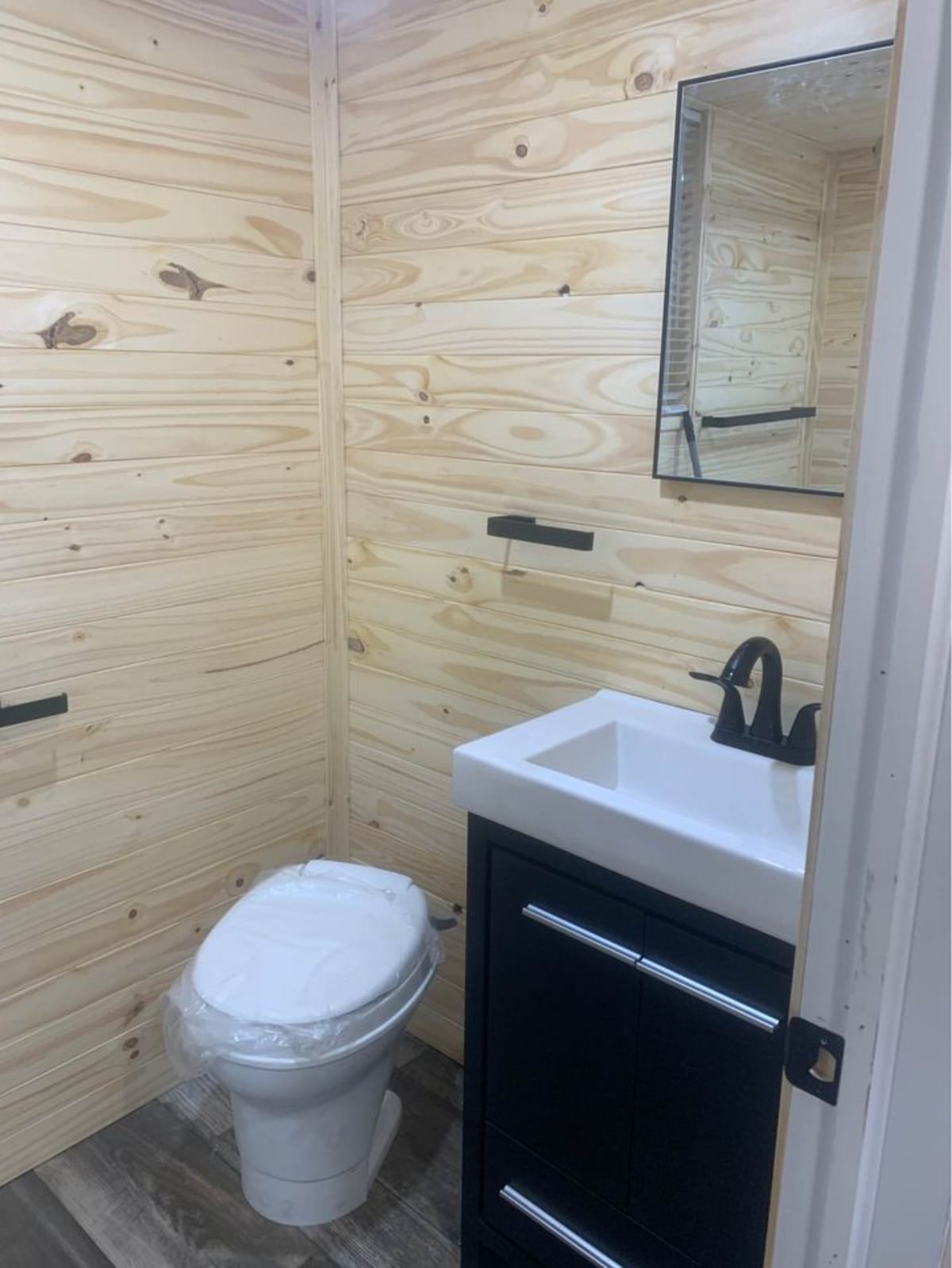 Bathroom area of Cozy Four Season Tiny House has a standard toilet and a sink with vanity
