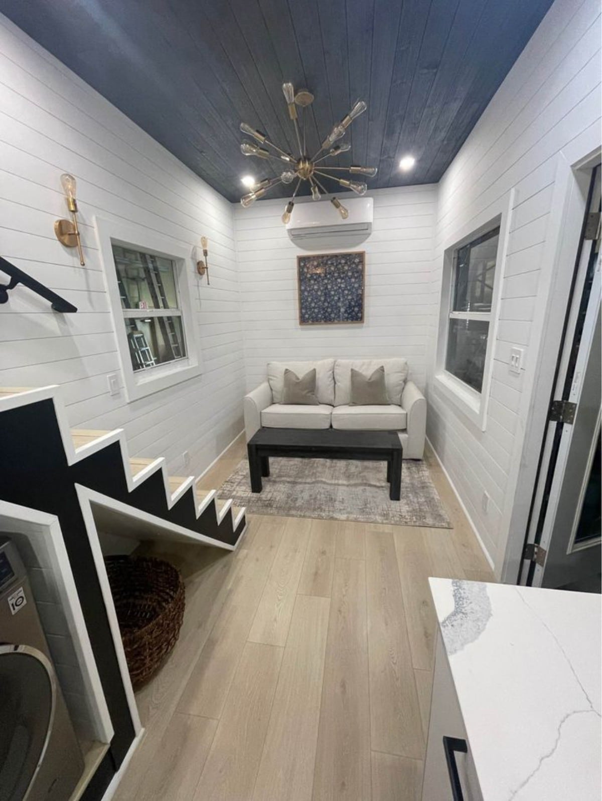 Stunning interior and living area of New 24' Luxury Tiny Home has a couch, coffee table, windows, chandelier and an air condition.