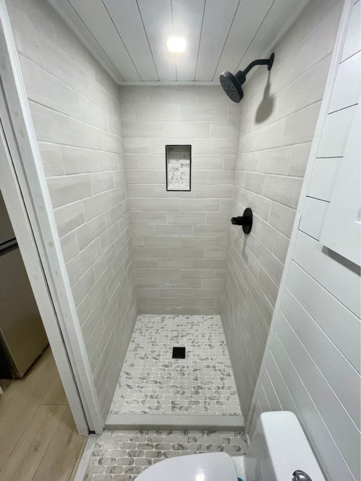 Super stylish bathroom has shower area, a standard toilet and water heater