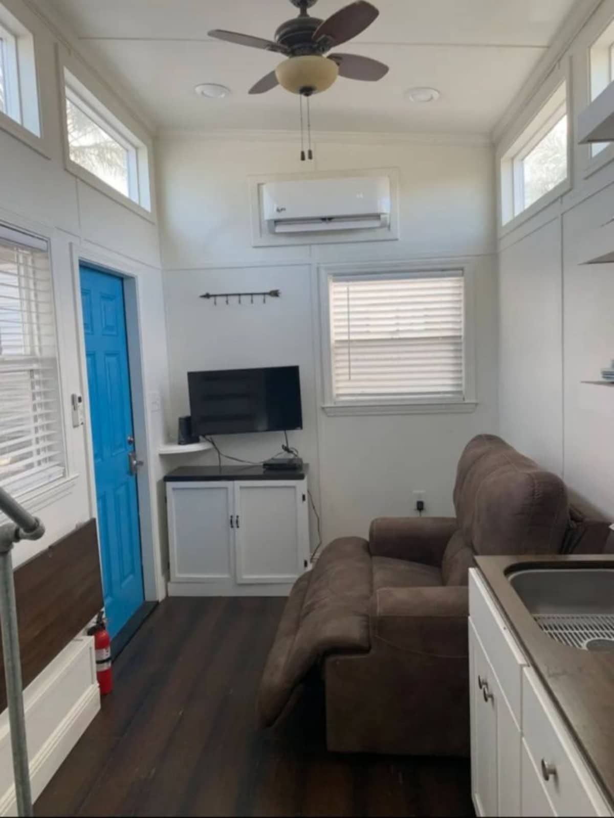 Living area of 22' Custom Tiny House has a recliner and wall mounted television set along with some storage and an air condition unit