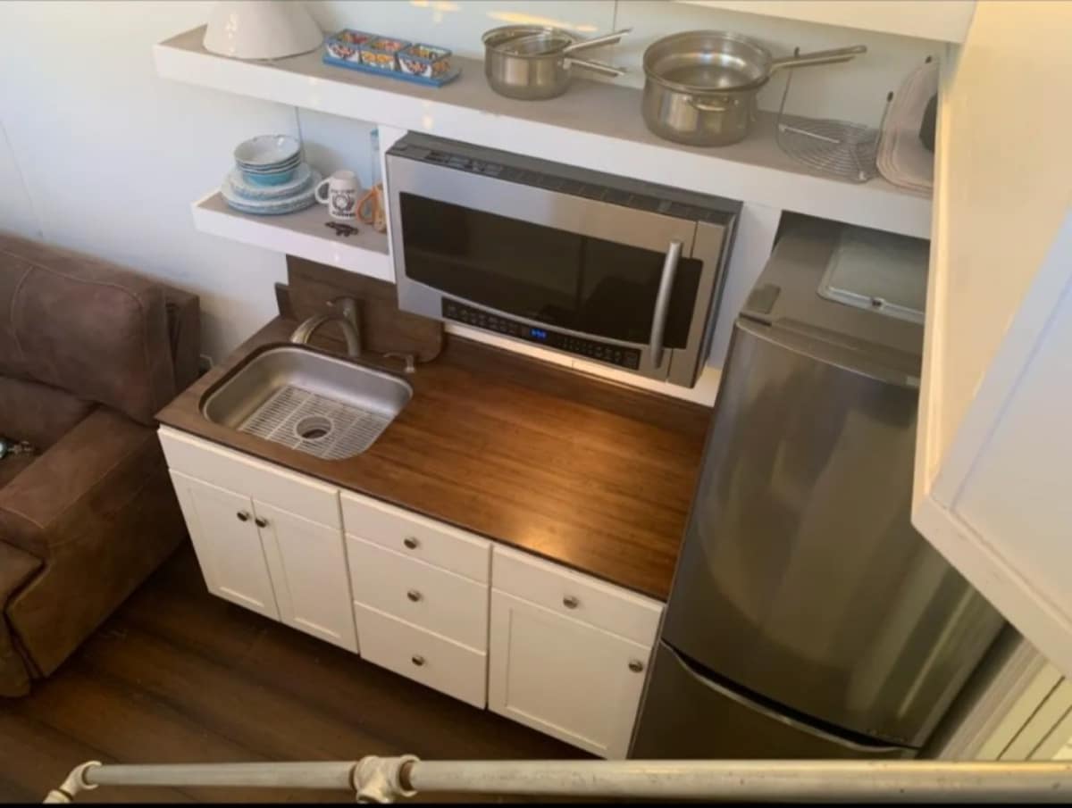 Granite countertop, sink, electric stove and refrigerator in kitchen area of 22' Custom Tiny House