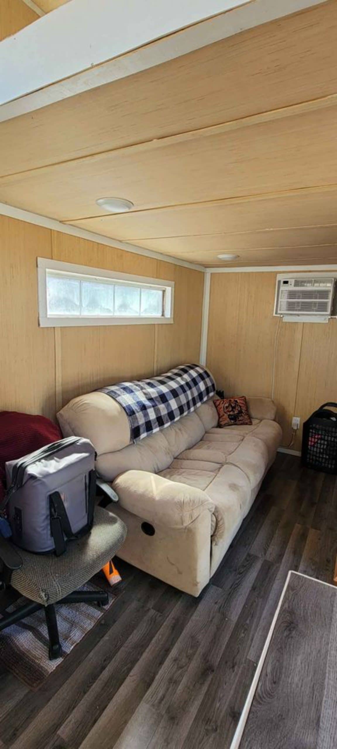Living area of 28' Budget Friendly Tiny House has a comfortable couch on 1 side