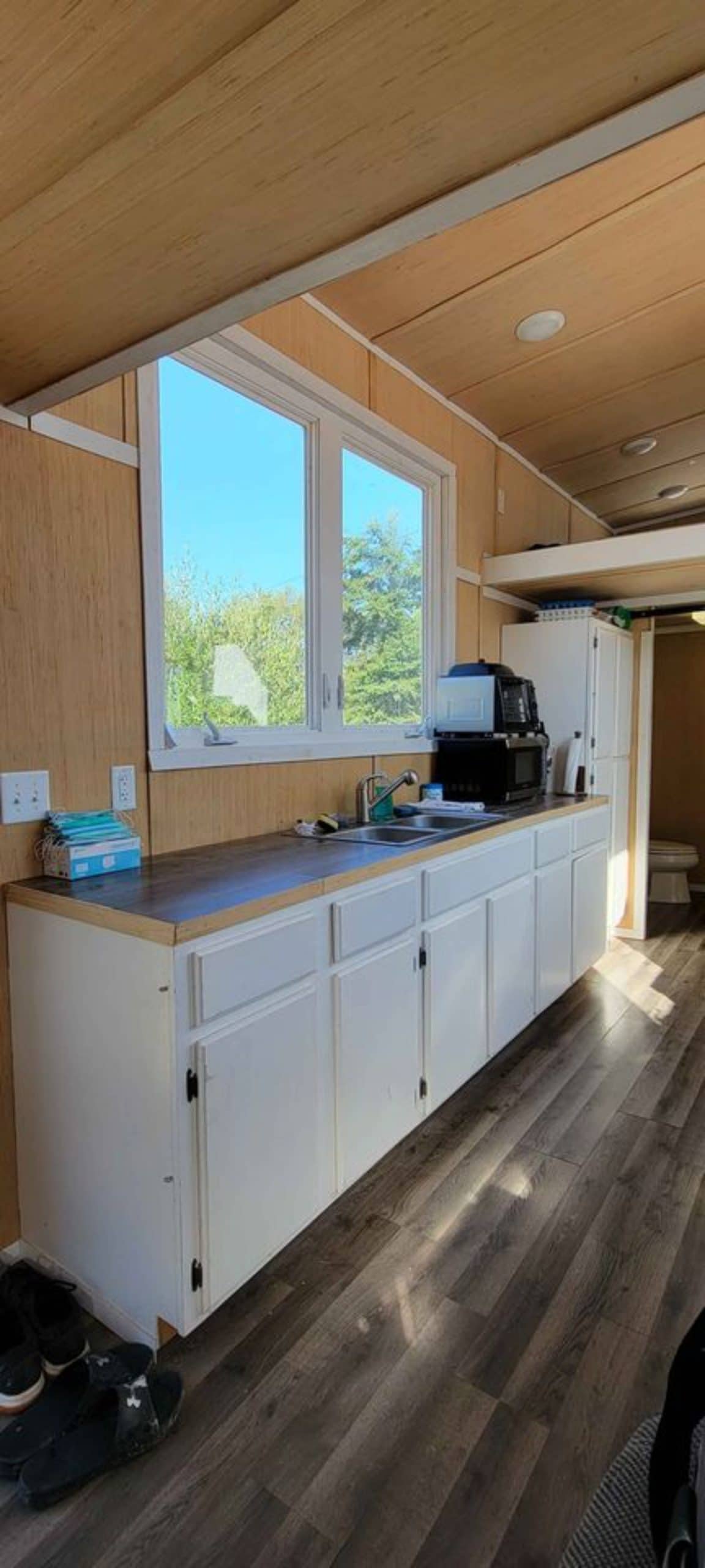 Kitchen area of 28' Budget Friendly Tiny House has countertop, oven and cooktop and lots of storage drawers