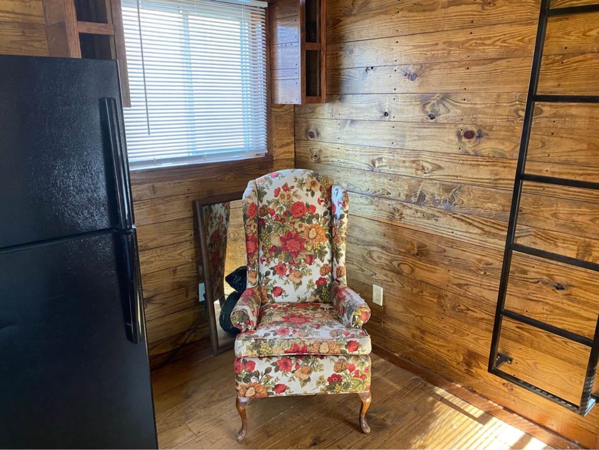 Living area of 36' Tiny House has a small wingback chair in the corner