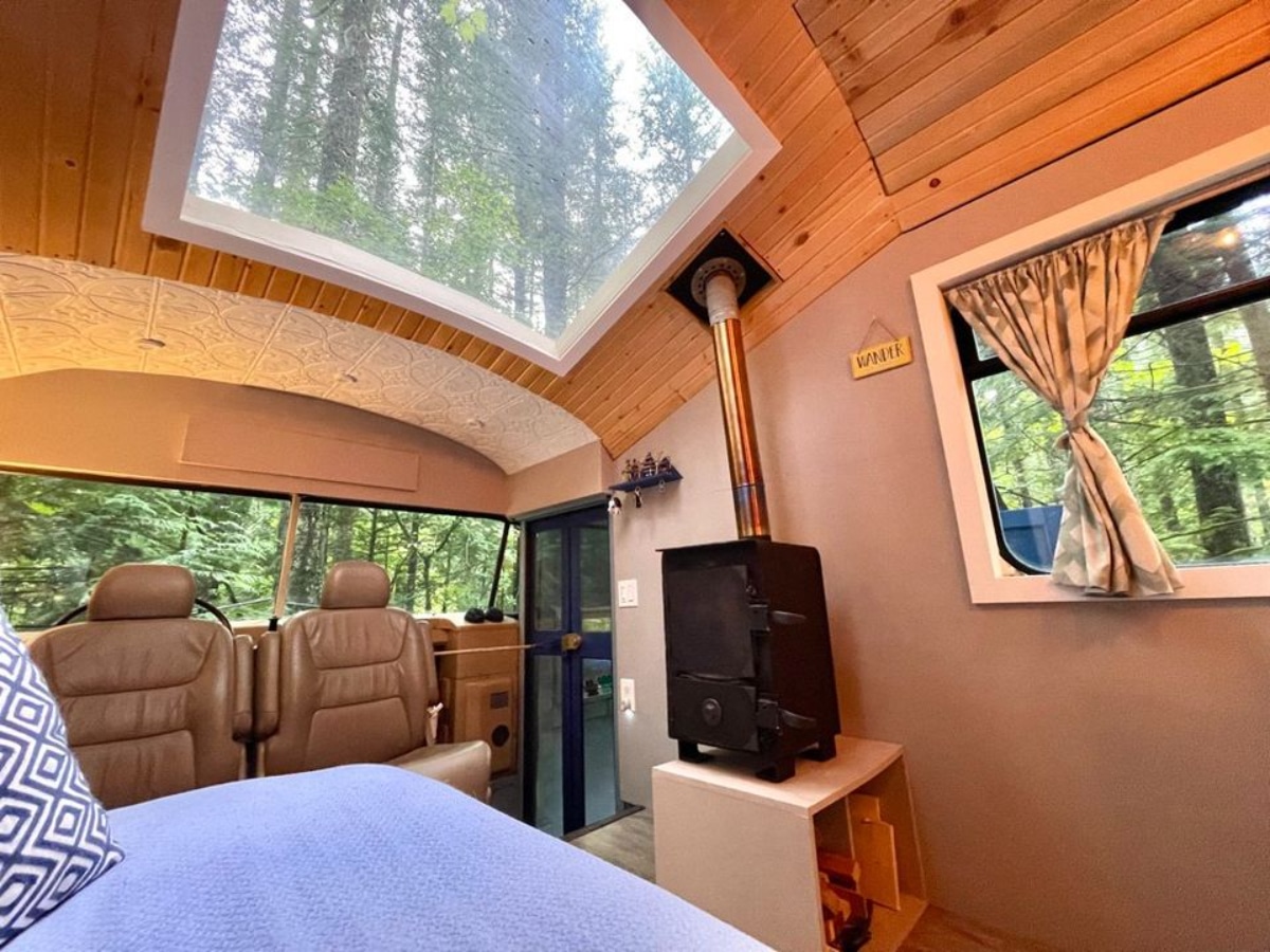 Living area of 40' School Bus Converted Tiny House has a couch and wood stove