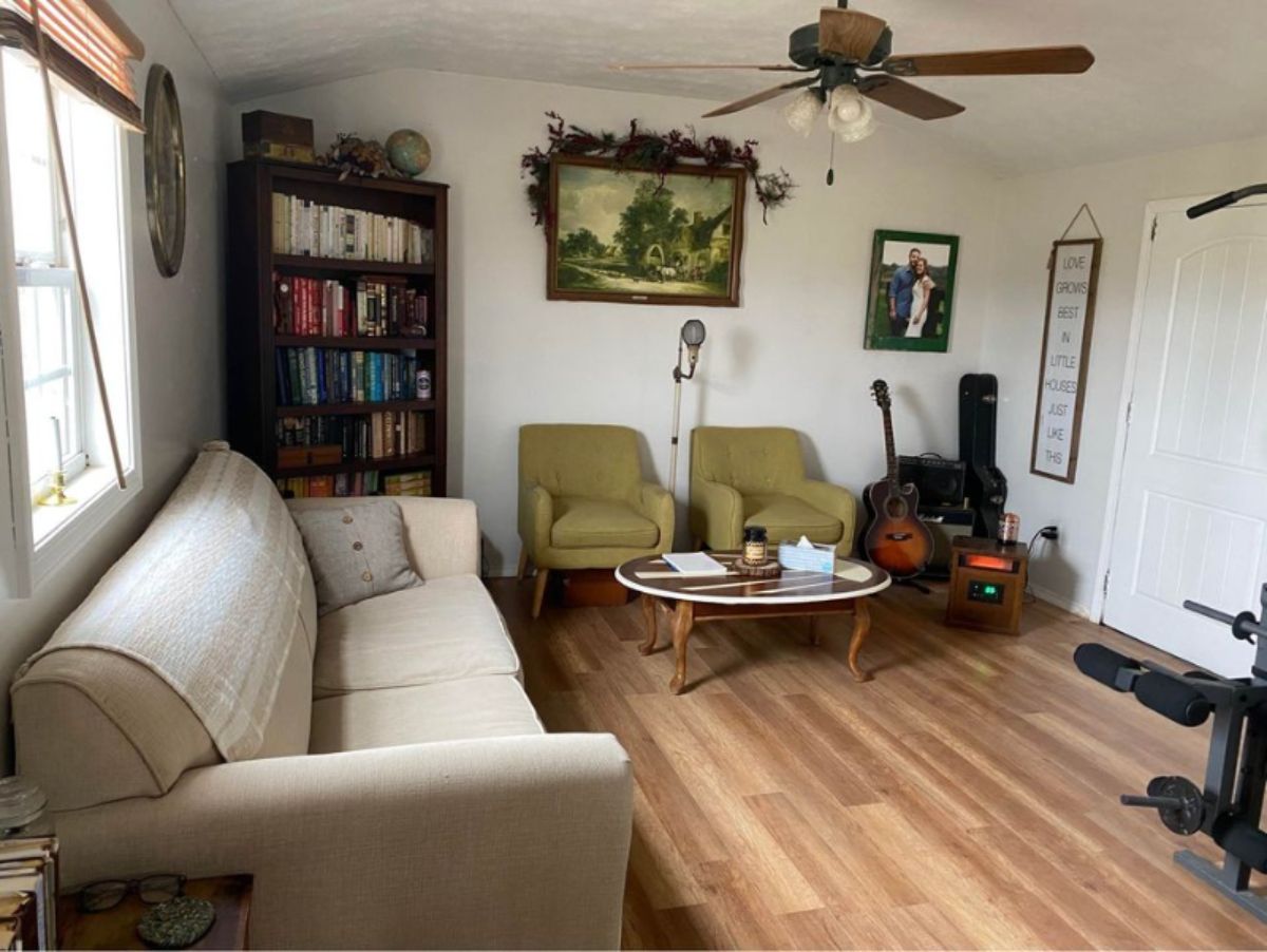 Living area of 40' Shed Converted Tiny House has a couch, chairs, coffee table and book shelf still ample space