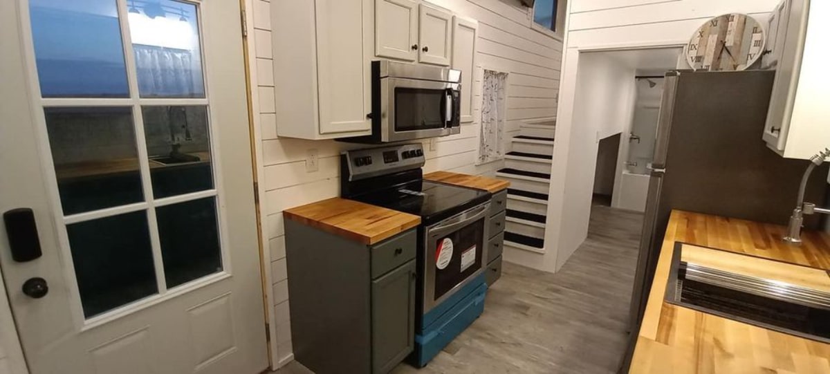 Kitchen area of 400 sf Tiny House has microwave oven, cooktop and refrigerator