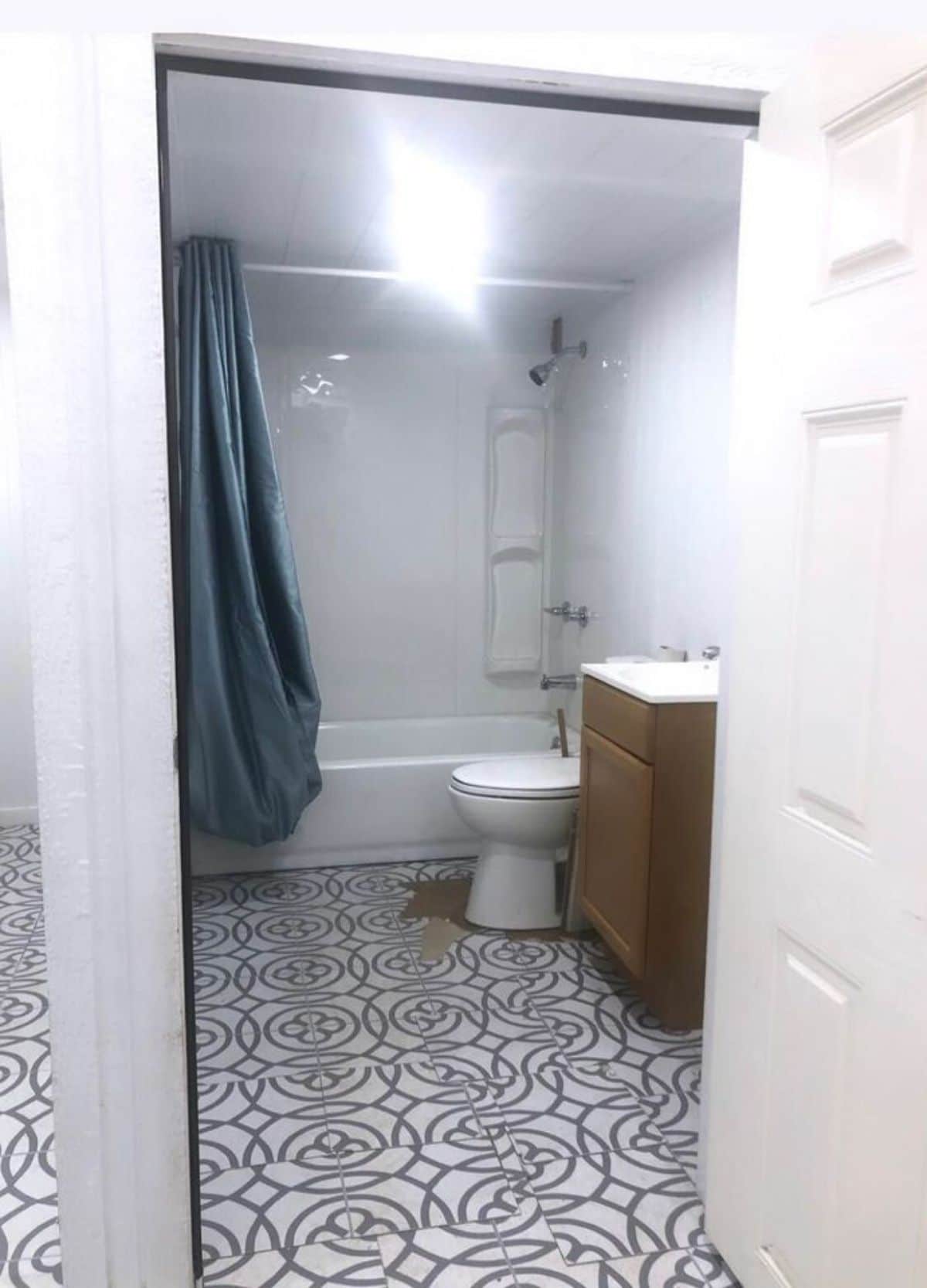 Bathroom of 24’ Tiny Cottage With Two Lofts has a small bath tub, toilet and sink