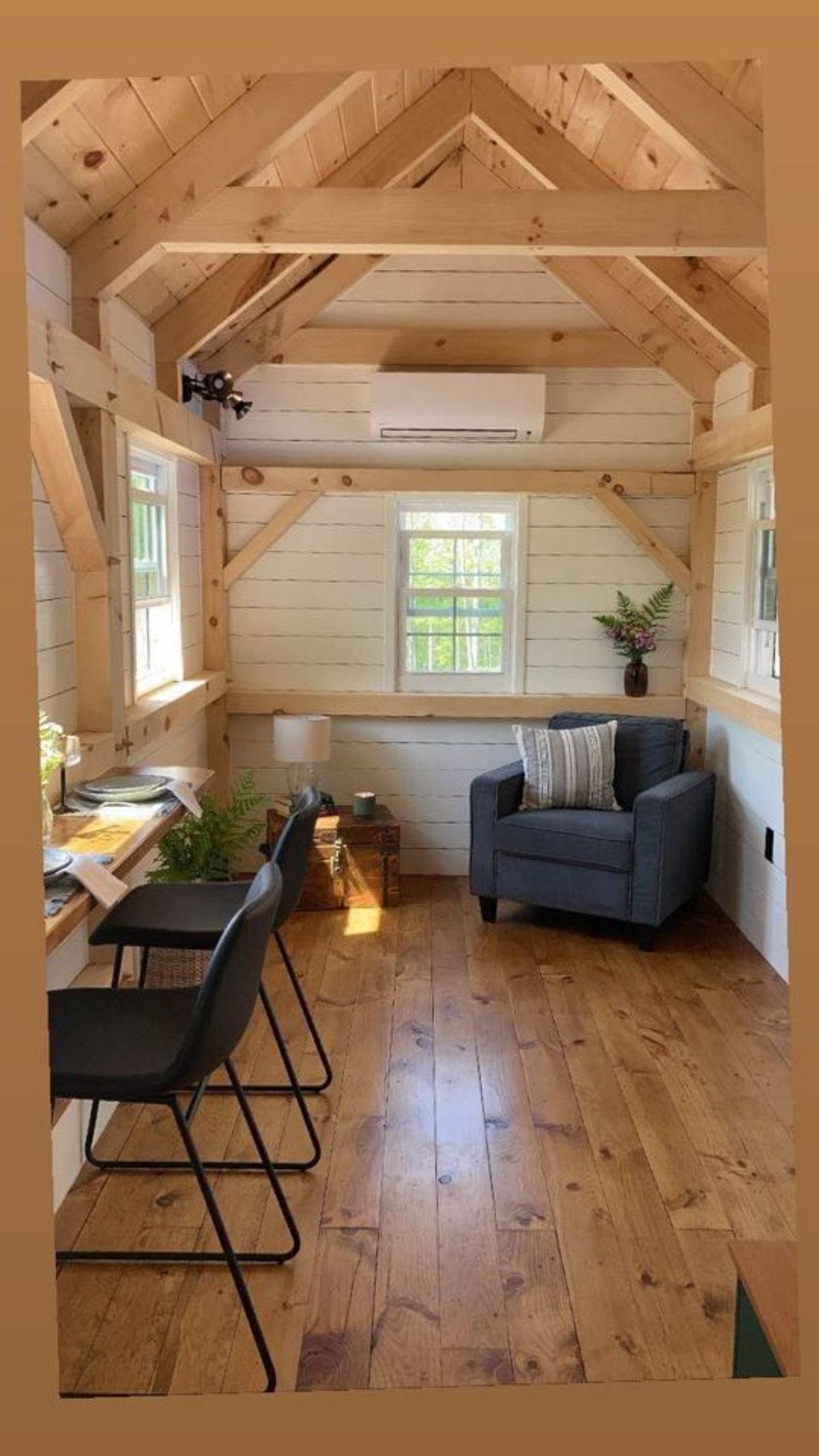 Living room of 26’ Timber Framed Tiny House has single seater couch and dining table with 2 chairs