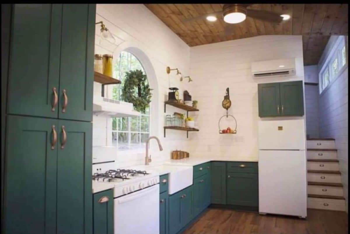 Kitchen area of 450 sf Tiny Home has propane gas, sink cabinets and refrigerator and wall mounted air-condition unit