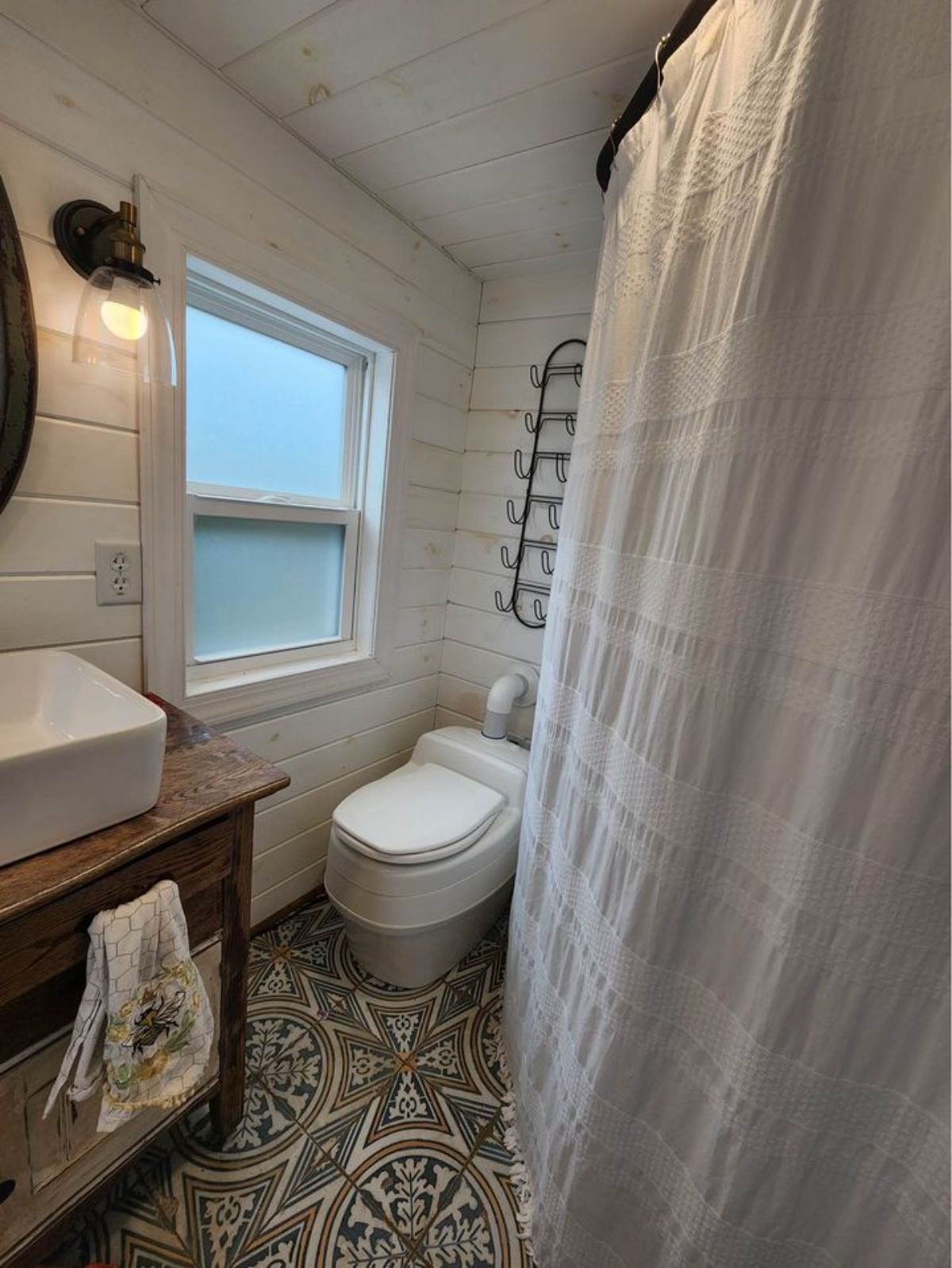 Bathroom of 450 sf Tiny Home has a standard toilet, sink with vanity and separate shower area